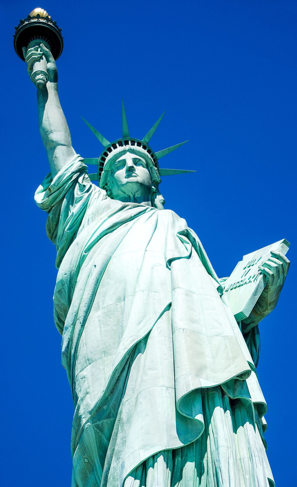 Statue of Liberty seen from below against a blue sky